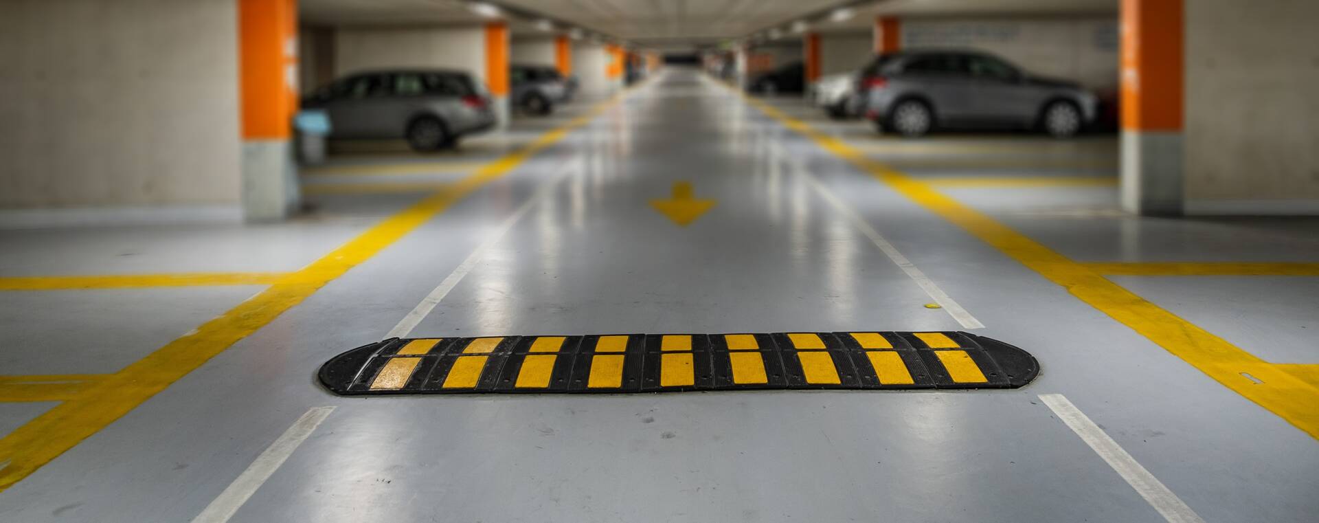 Yellow markings with blurred modern cars parked inside closed underground parking lot.