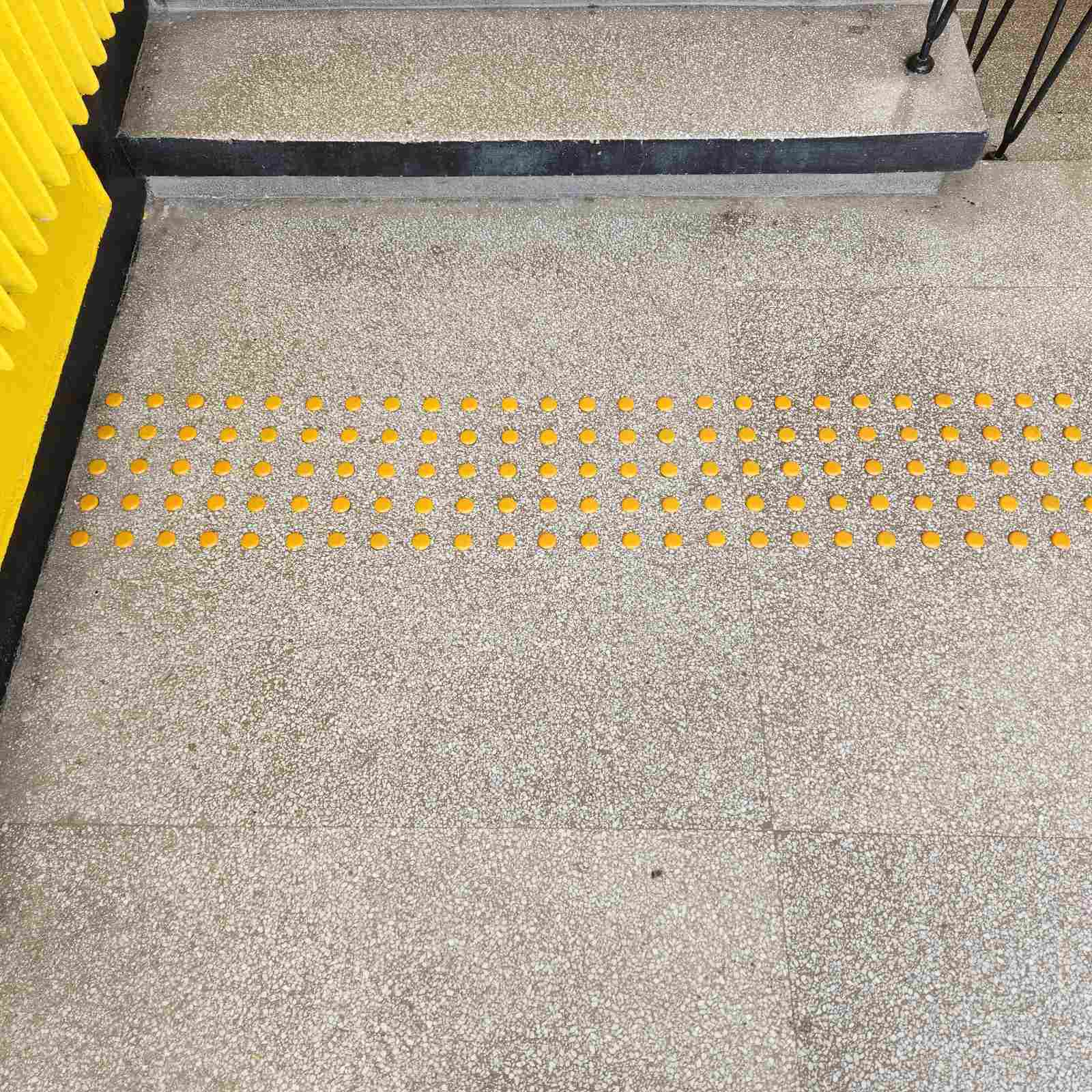 montaj-taktilni-butoni-pred-stulbi-tereno-eko.jpg Butoane tactile galbene instalate în fața primei trepte a unei scări de către Tereno Eco pentru a semnaliza un pericol.
